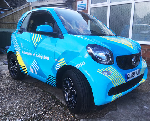 Small car with a blue car wrap